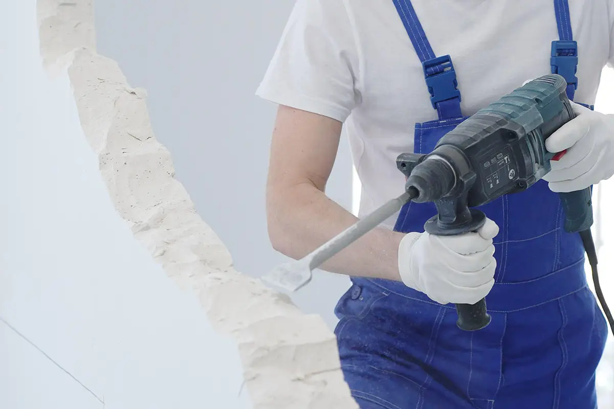 Kaiserfeld Entrümpelung Ein Mann mit Latzhose beim Abbruch einer Wand